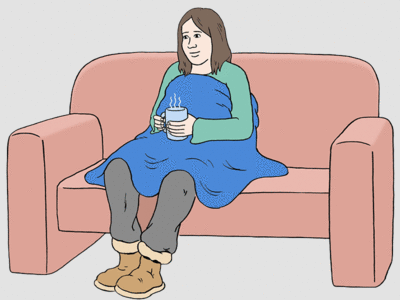 Auf dem Foto sitzt eine Frau auf einem Sofa. Sie ist mit einer Decke zugedeckt und hält eine dampfende Tasse Tee in den Händen.